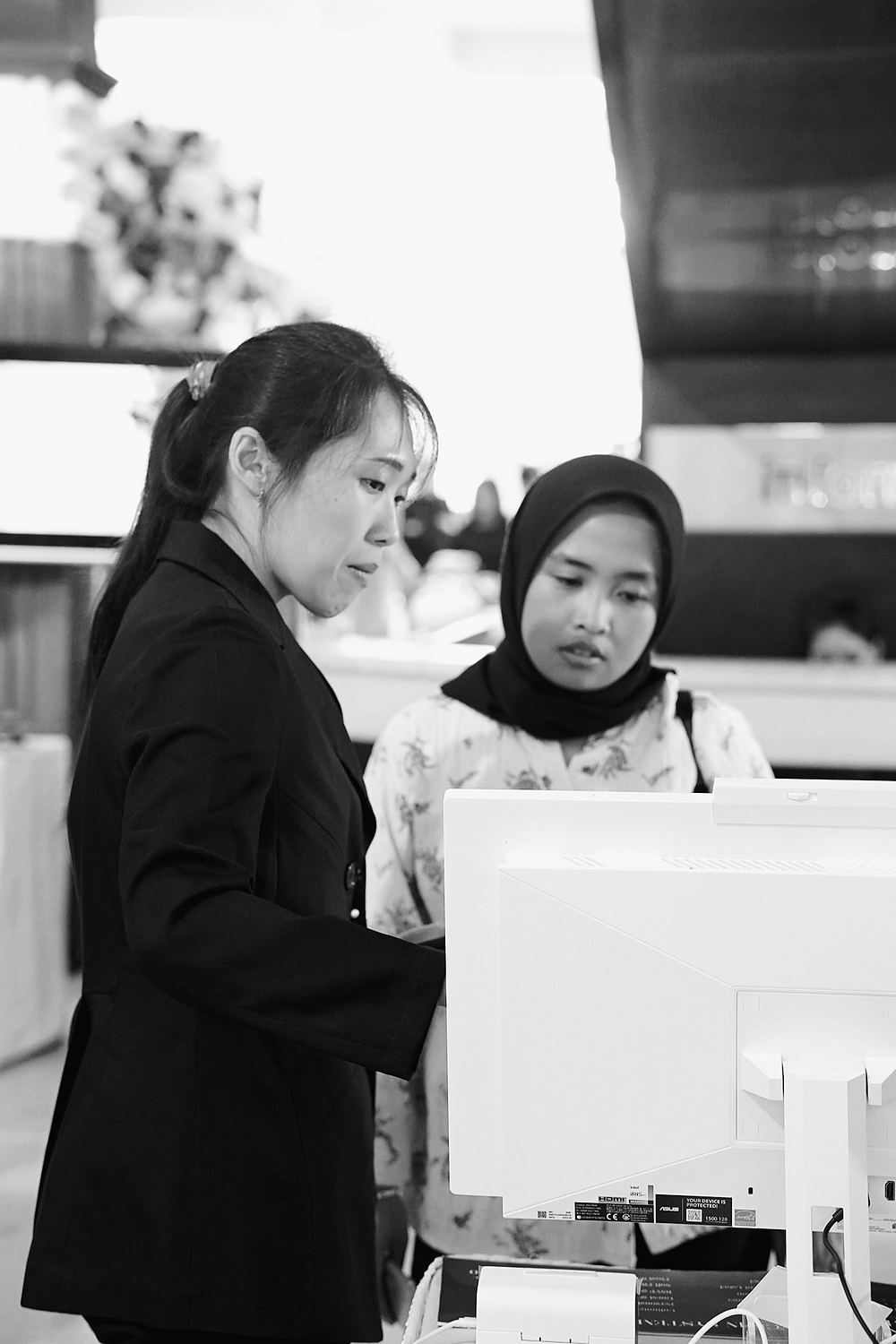 Petugas Invitamu membantu tamu di meja check-in